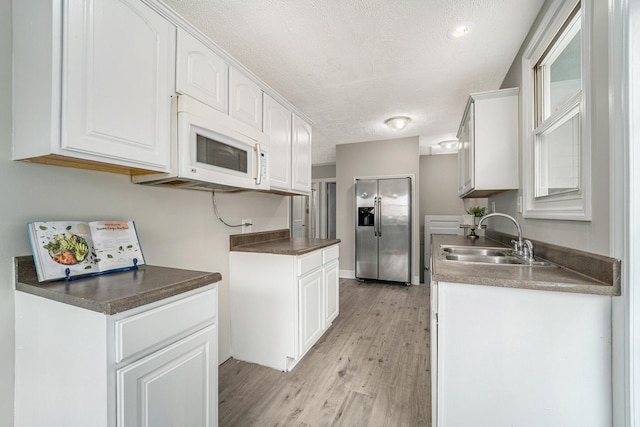 kitchen with white cabinetry, sink, and stainless steel refrigerator with ice dispenser