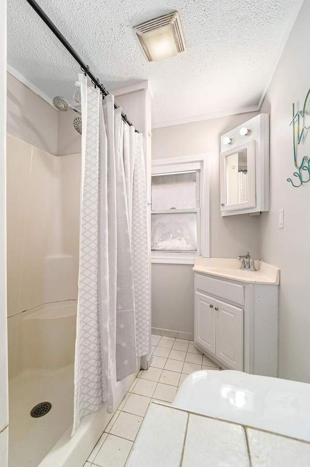 bathroom with tile patterned flooring, vanity, a textured ceiling, and walk in shower