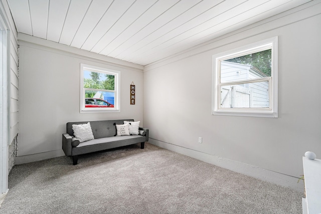 sitting room with carpet floors, crown molding, and wooden ceiling