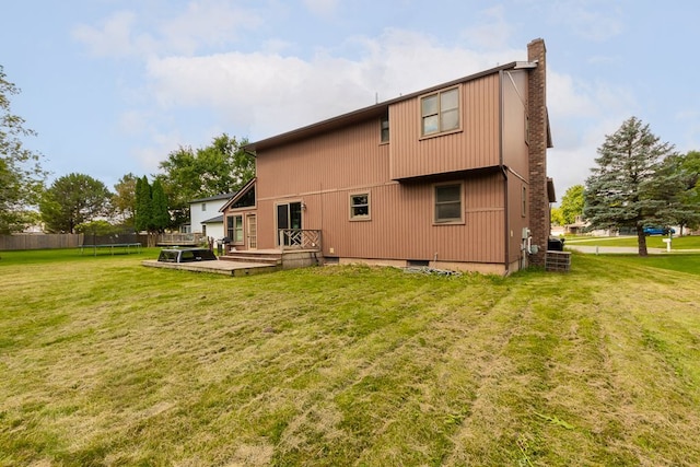 rear view of property featuring a yard and a wooden deck