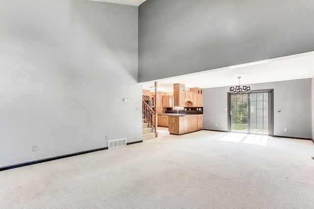 unfurnished living room featuring a notable chandelier and light colored carpet