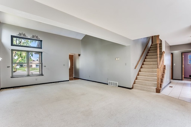 unfurnished living room featuring carpet and a high ceiling