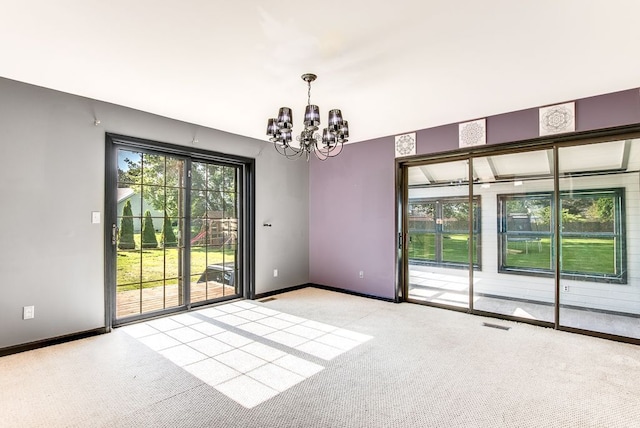 carpeted empty room with an inviting chandelier