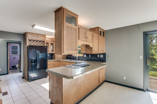 kitchen featuring kitchen peninsula, backsplash, black fridge with ice dispenser, sink, and light tile patterned floors