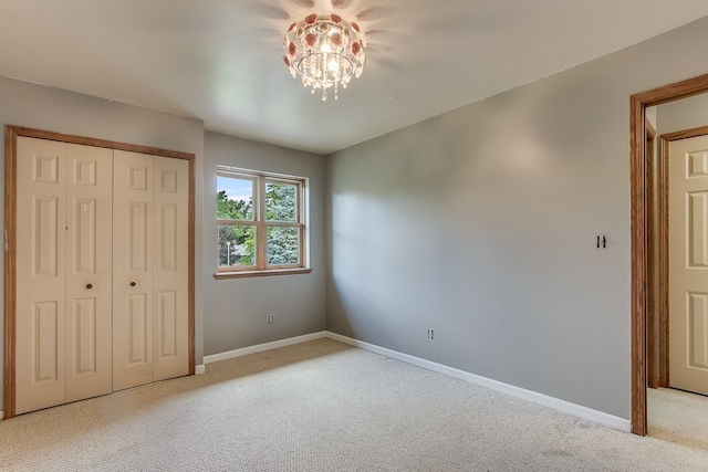 unfurnished bedroom with an inviting chandelier, light carpet, and a closet