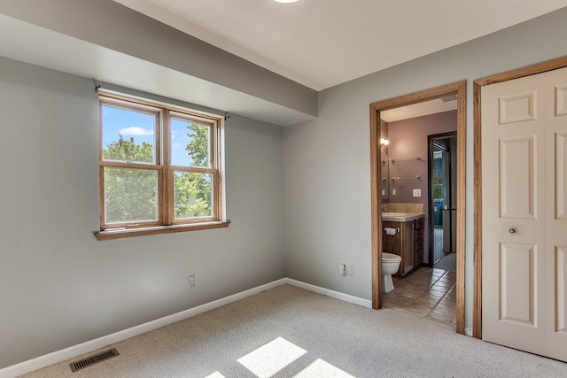 unfurnished bedroom with ensuite bathroom, carpet floors, sink, and a closet