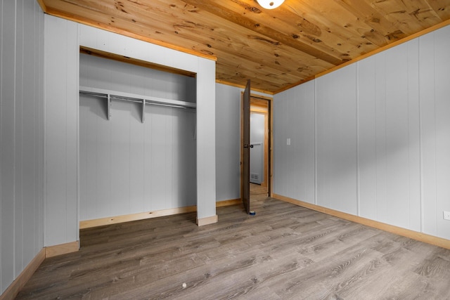 unfurnished bedroom with hardwood / wood-style flooring, wood walls, wooden ceiling, and a closet