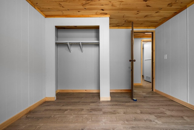 unfurnished bedroom with wood walls, wood-type flooring, a closet, and wooden ceiling