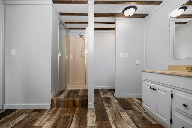 bathroom with beam ceiling, hardwood / wood-style flooring, vanity, and walk in shower