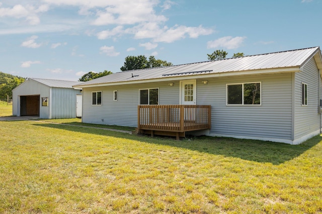 rear view of house featuring a lawn, a garage, an outbuilding, and a deck