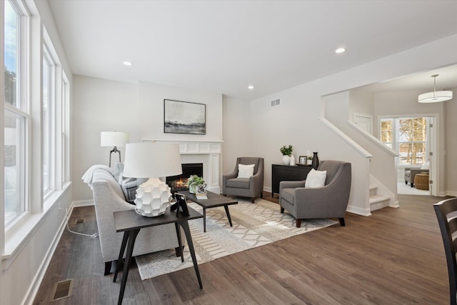 living room with a high end fireplace, visible vents, recessed lighting, and wood finished floors