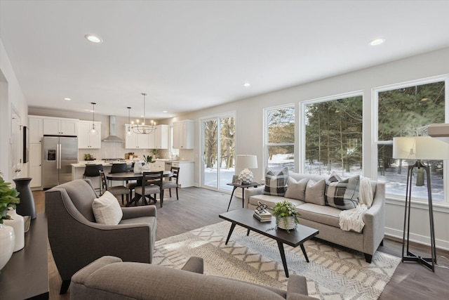 living area with a notable chandelier, baseboards, wood finished floors, and recessed lighting