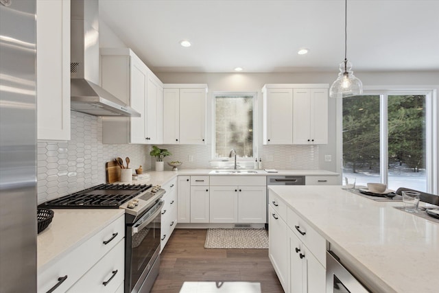 kitchen featuring gas range, wall chimney exhaust hood, dark wood-style flooring, white cabinetry, and a sink