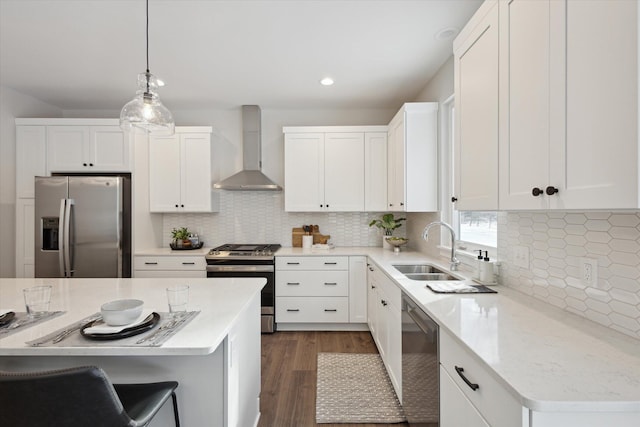 kitchen featuring stainless steel appliances, a sink, white cabinetry, wall chimney exhaust hood, and pendant lighting