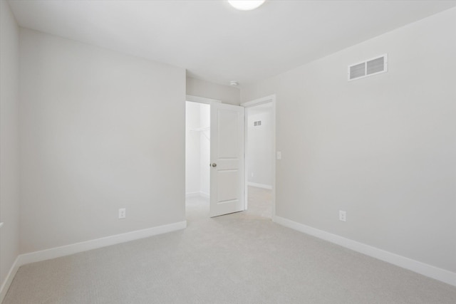 spare room featuring light carpet, baseboards, and visible vents