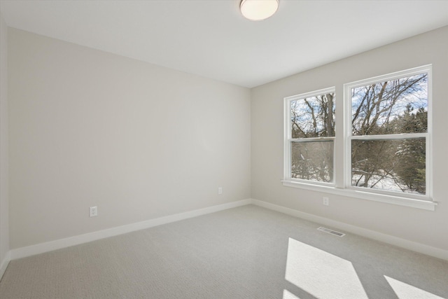 unfurnished room with carpet floors, visible vents, and baseboards