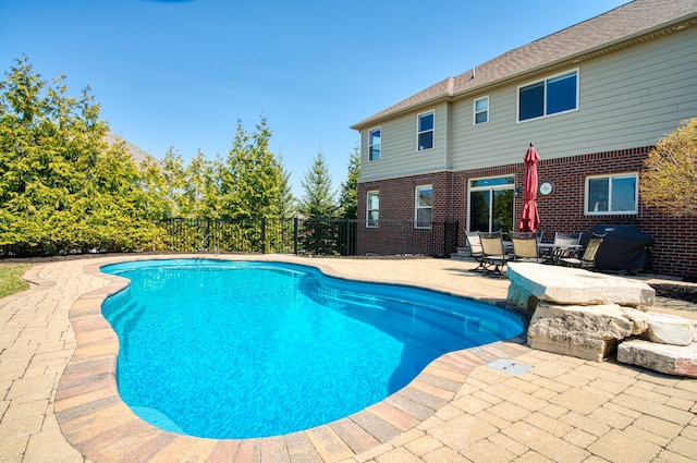 view of swimming pool featuring fence, a fenced in pool, area for grilling, and a patio