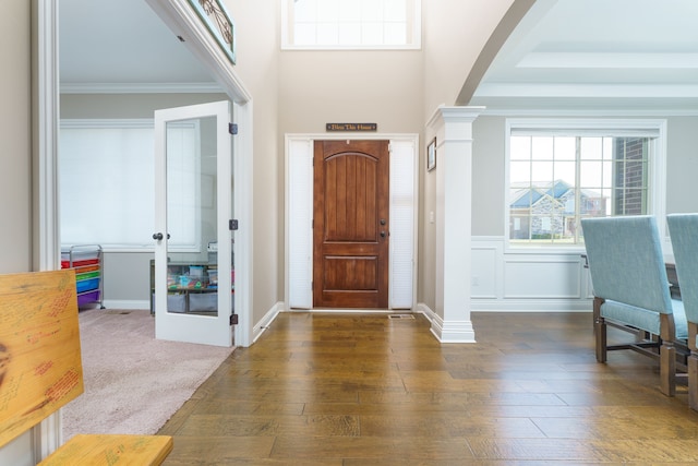 foyer with arched walkways, ornate columns, crown molding, and hardwood / wood-style flooring