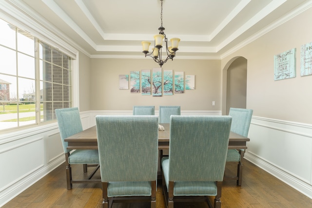 dining space featuring arched walkways, an inviting chandelier, a raised ceiling, and dark wood-style flooring