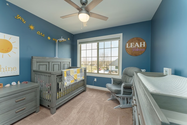 carpeted bedroom with a nursery area, baseboards, and ceiling fan
