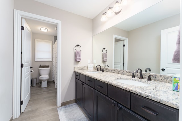 full bath with baseboards, a sink, double vanity, and toilet