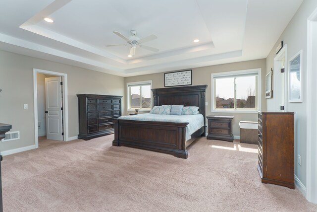 bedroom with light colored carpet, a tray ceiling, visible vents, and recessed lighting