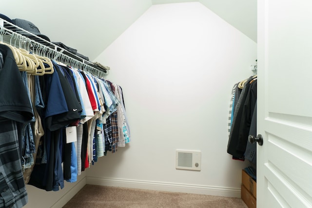 walk in closet with carpet floors, visible vents, and lofted ceiling