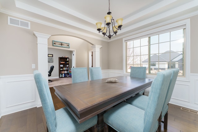 dining space with a wealth of natural light, a tray ceiling, visible vents, and ornate columns