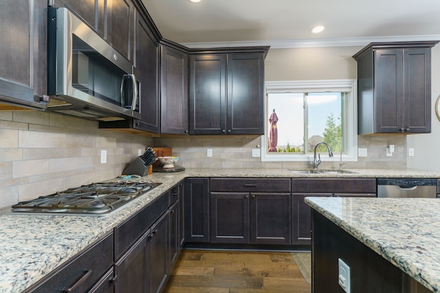 kitchen featuring light stone counters, a sink, dark brown cabinetry, stainless steel appliances, and dark wood-style floors