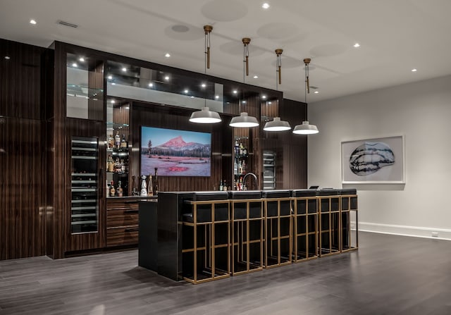 bar featuring wine cooler, hanging light fixtures, and wood-type flooring