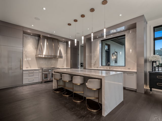 kitchen featuring wall chimney exhaust hood, sink, decorative light fixtures, double oven range, and dark hardwood / wood-style floors