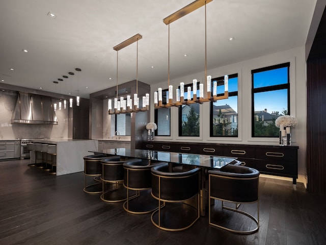 interior space featuring pendant lighting, backsplash, dark hardwood / wood-style floors, and wall chimney range hood