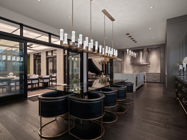 bar featuring wall chimney exhaust hood, pendant lighting, and dark hardwood / wood-style floors