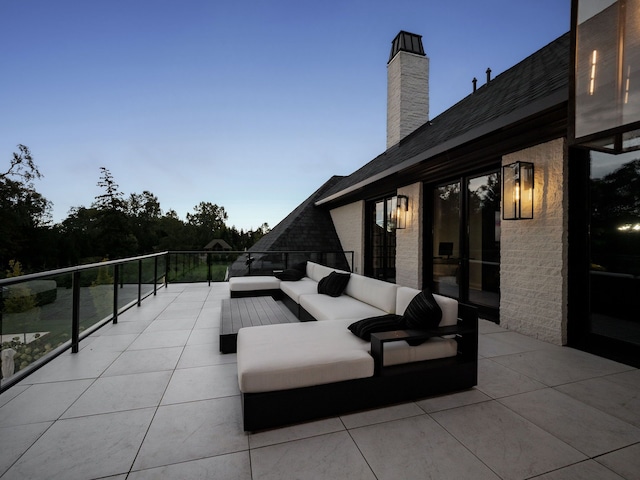 patio terrace at dusk with outdoor lounge area and a balcony