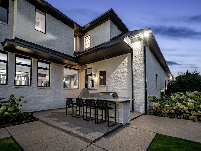 patio terrace at dusk featuring area for grilling and a grill