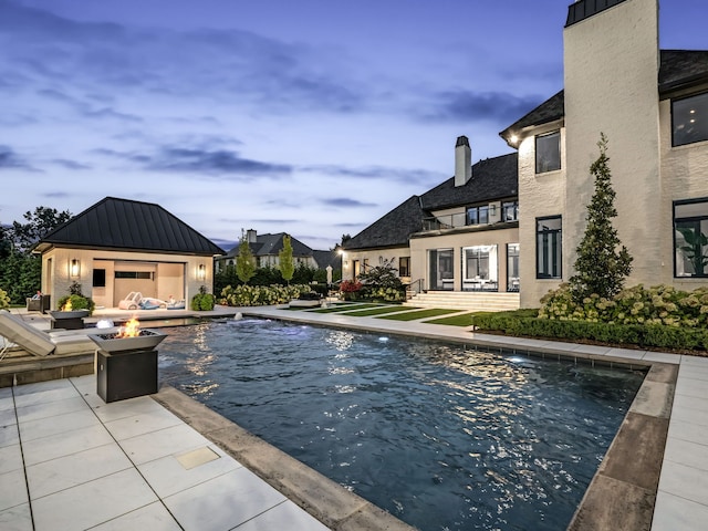 pool at dusk featuring a patio and an outdoor fire pit