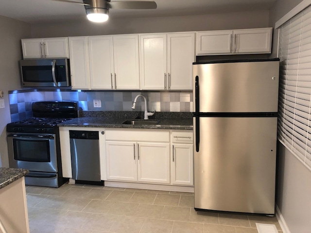 kitchen featuring sink, backsplash, dark stone counters, white cabinets, and appliances with stainless steel finishes