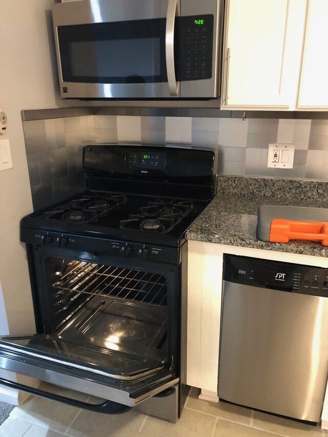 32520 Newaygo St, Westland, MI 48186 - kitchen featuring appliances with stainless steel finishes, tasteful backsplash, white cabinets, light tile patterned flooring, and dark stone counters