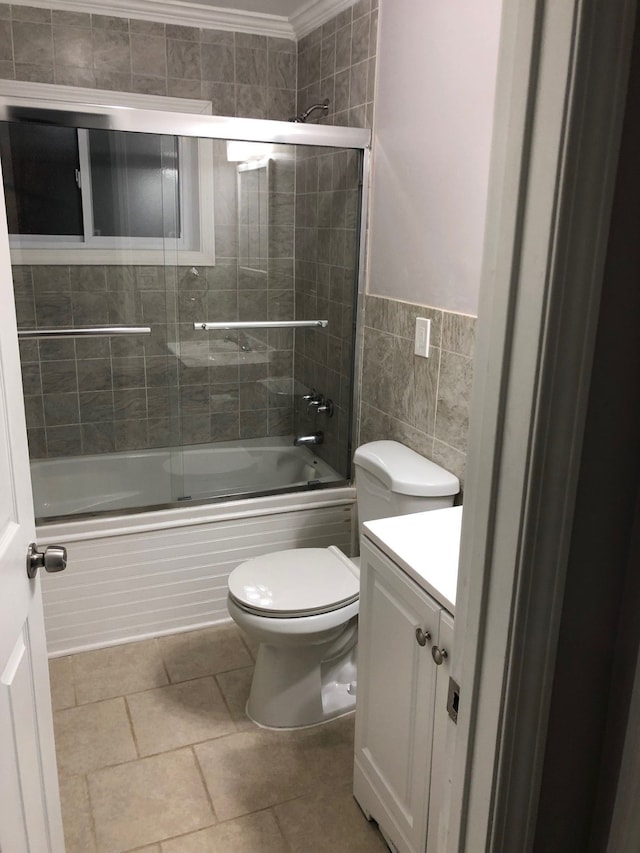 full bathroom featuring ornamental molding, vanity, tile walls, enclosed tub / shower combo, and toilet