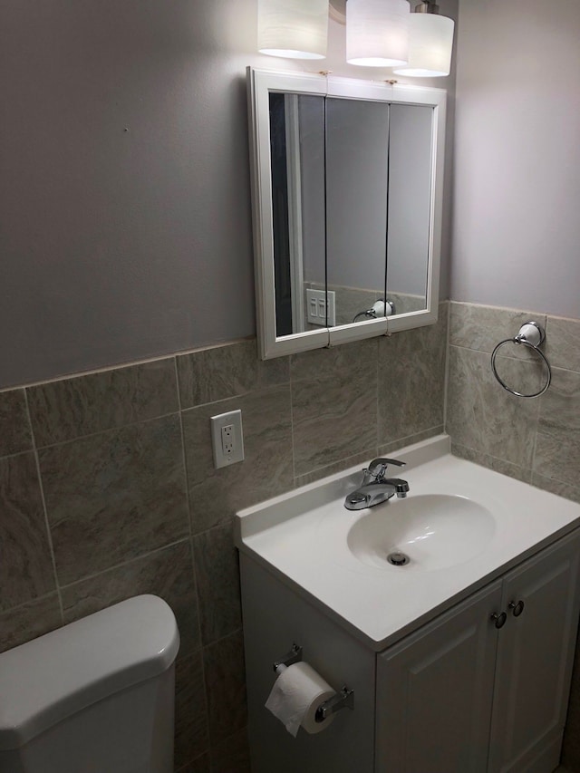 bathroom featuring vanity, toilet, and tile walls