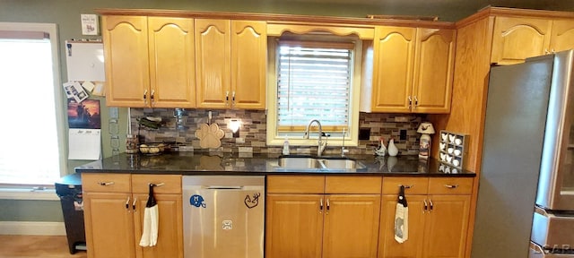 kitchen with stainless steel appliances, tasteful backsplash, dark stone counters, and sink