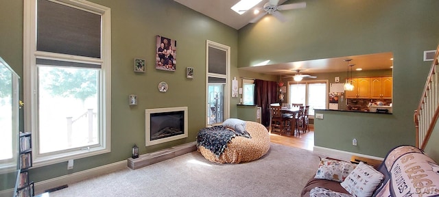 living room featuring a skylight, ceiling fan, and light colored carpet