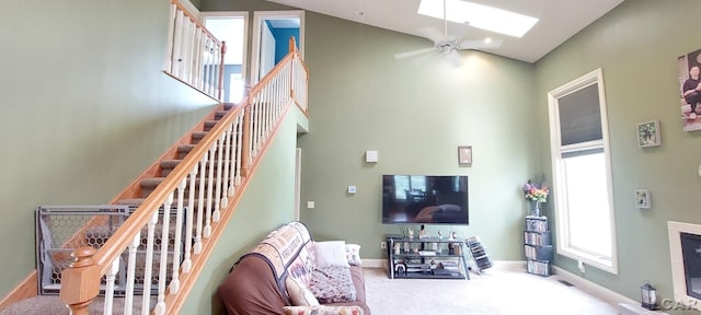 carpeted living room featuring ceiling fan and lofted ceiling with skylight