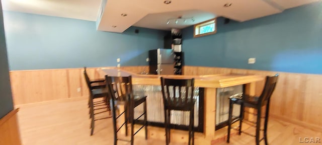 interior space with wooden walls, light wood-type flooring, light brown cabinetry, and stainless steel refrigerator