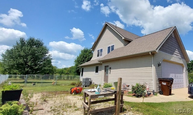 rear view of house with a garage, a lawn, and central air condition unit