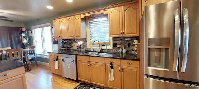 kitchen featuring sink, light hardwood / wood-style flooring, decorative backsplash, ceiling fan, and stainless steel appliances