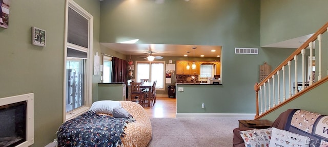 carpeted living room with a towering ceiling and ceiling fan