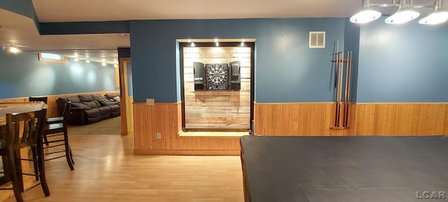 dining space with light wood-type flooring and wooden walls