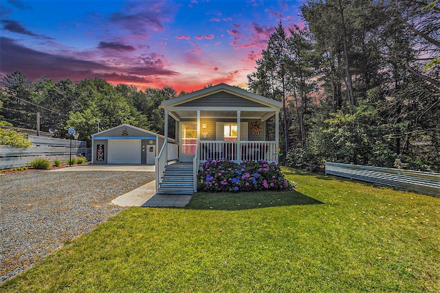 view of front of property featuring an outbuilding, a yard, a garage, and covered porch