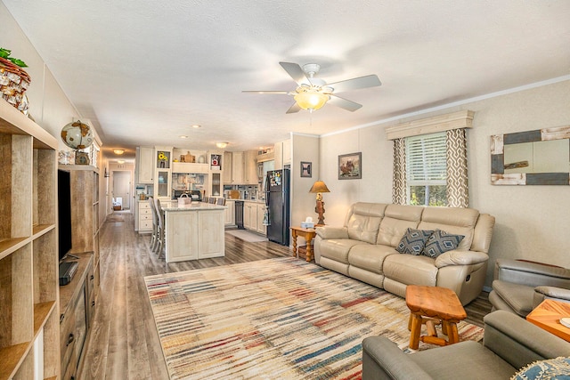 living room featuring ceiling fan, hardwood / wood-style floors, a textured ceiling, and ornamental molding